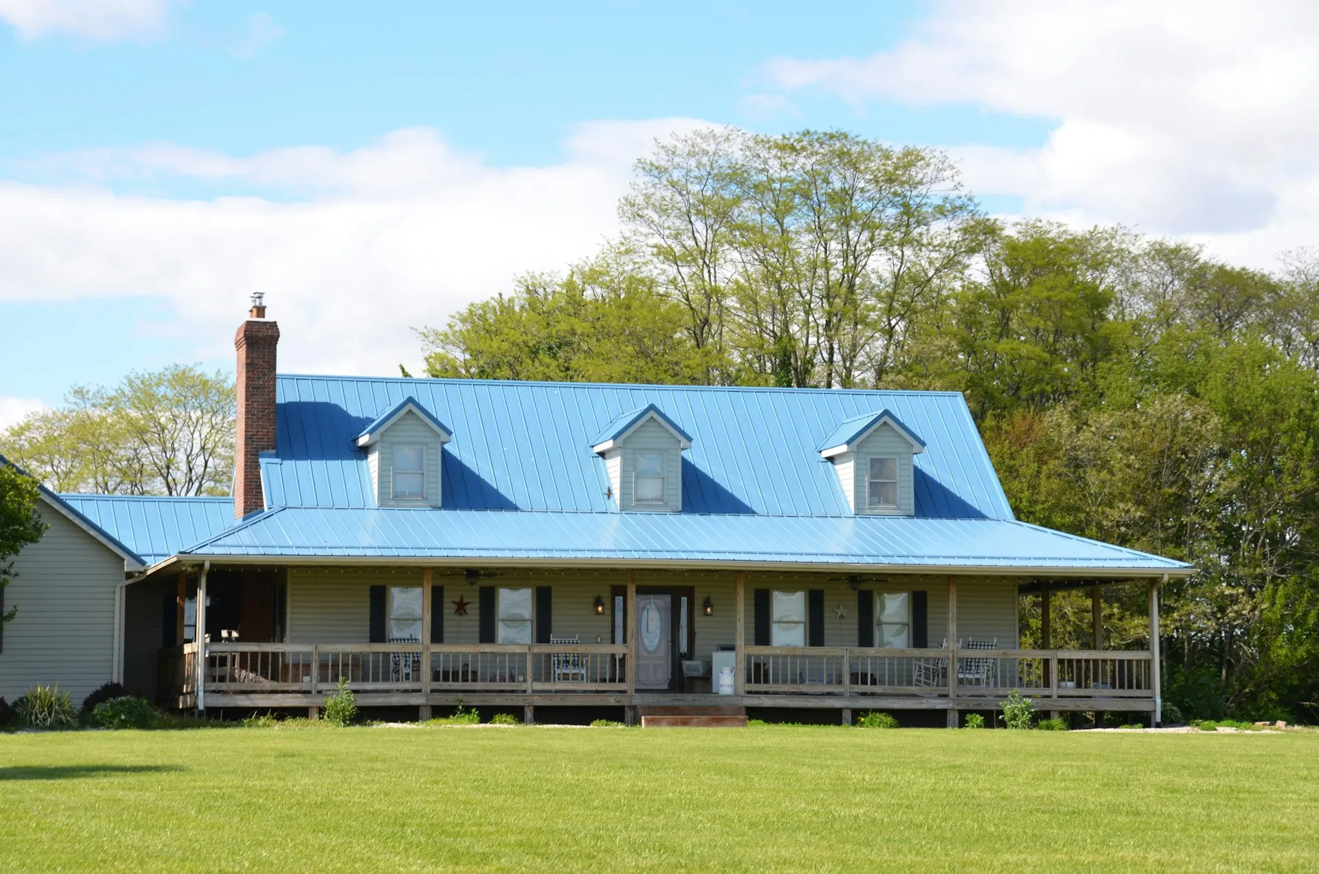American home with a wraparound porch on a tree-lined lot